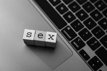 Wooden blocks spelling the word SEX on a laptop keyboard, representing online discussions about gender and sexualit
