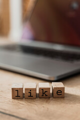 Wooden blocks spelling LIKE on laptop, concept of social media engagement, digital approval, and online interaction