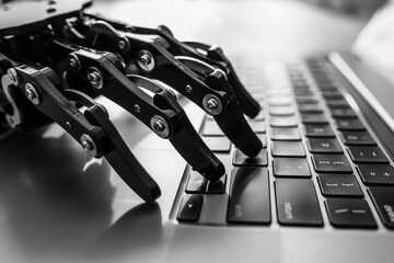 Robotic hand typing on laptop keyboard, concept of artificial intelligence and automation