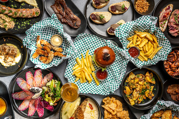 Top view of assorted bar food and snacks on dark table