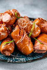 Grilled sausages with cheese and herbs on a blue plate