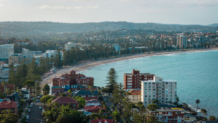 Obraz premium Stunning panoramic views of Manly Beach with soft golden sands and gentle waves glistening beneath the clear blue sky.