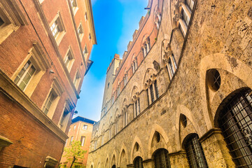 Obraz premium Photo of a narrow medieval street in Siena showing rustic stone facades, Tuscan details, charming alleys and authentic old town atmosphere in Tuscany Italy