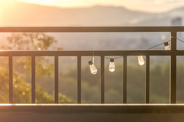Nature travel background image, golden light hits the light bulbs hanging on the fence in the evening.