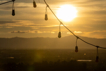 Nature travel background image, golden light hits the light bulbs hanging on the fence in the evening.