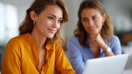 Obraz premium Businesswoman working diligently on laptop while discussing strategic plans with her female colleague in comfortable boardroom setting | strategic planning laptop collaboration