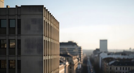 Modern artful building facade against a blurred cityscape and a clear sky with a hint of the sun