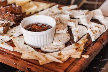 Rustic wooden board presenting sliced goat cheese and a ramekin of fig jam, creating a gourmet appetizer