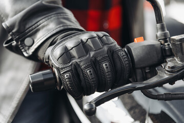 man hand in black leather glove on motorcycle handle, close up view, safety on road, riding motorcycle concept © Anton Pentegov
