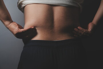 Asian fat man in front of a mirror looks at his body. Excess belly fat, Unhealthy lifestyle, Diet concept.