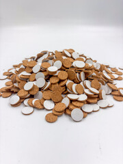 Large heap of small round cork pads with white peel-off liners piled on a clean white studio background, shown in close macro detail.