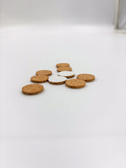 A small arrangement of self-adhesive cork pads scattered on a white surface, highlighting the thin circular shape and protective backing