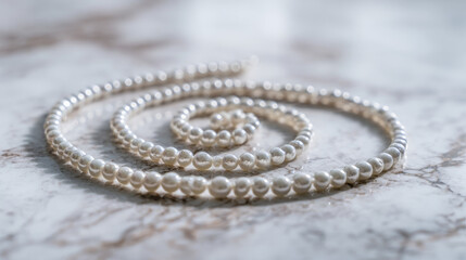 A pearl necklace arranged in the shape of a spiral galaxy on white marble 