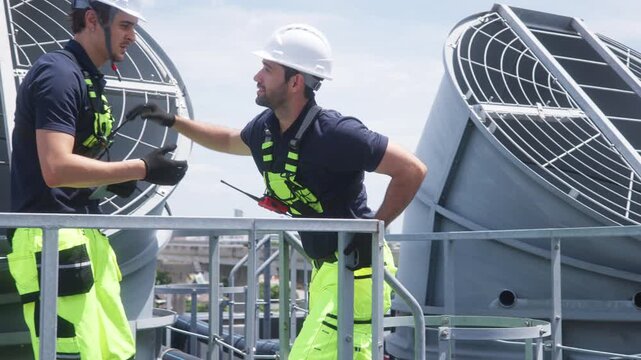 Engineers inspecting HVAC cooling systems on rooftop
