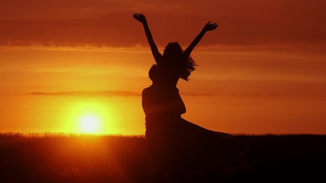 Silhouettes of a man and woman against the backdrop of sunset, lovers in an intimate moment. Concept love story. Super slow-motion shot.