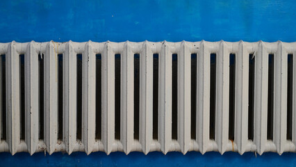 Old cast-iron radiator painted white, on a blue wall.