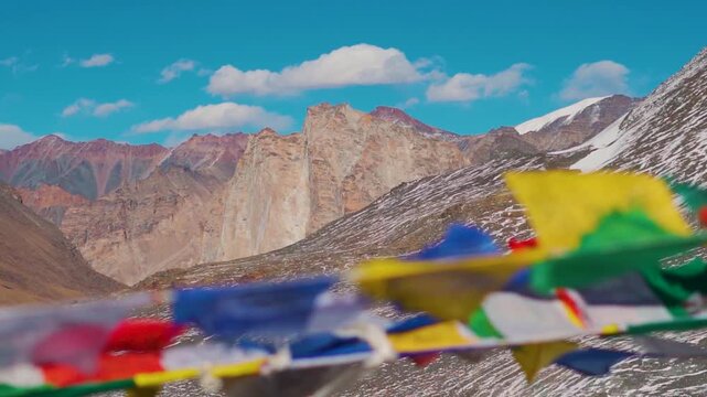 Handheld shot of Holy Gonbo Rangjon mountain as seen from Shinkula Pass with defocused prayer flags waving in the wind at Shinkula Top in Lahaul and Spiti district, Himachal Pradesh, India. 
