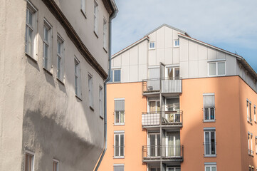 Historisches Wohngebäude aus dem 15. Jahrhundert mit vorkragenden Stockwerken im Streiflicht vor modernem Wohngebäude mit Balkonen in der Altstadt von Nördlingen