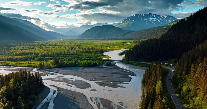 Flight over the branching river flowing at the mountain foot. Stunning scenery of Alaska, USA.