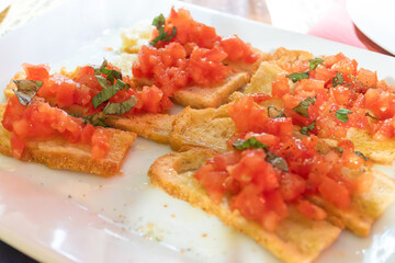Starter in italian restaurants, bread bruschetta roasted homebaked bread with olive oil and chopped ripe tomatoes and pesto