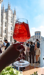 Drinks in Milan, tasting of traditional italian cocktail with sparkling wine Prosecco, orange, campari bitter liquor in bar with view on Duomo Milan, Italy