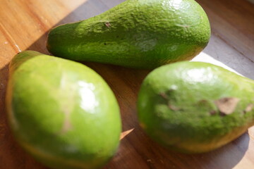 Three Ripe Avocados Resting on a Wooden Surface, Ready for Culinary Delights