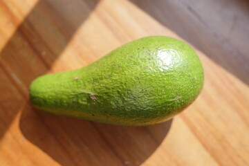 Fresh green avocado fruit on a wooden surface, healthy eating and natural ingredient