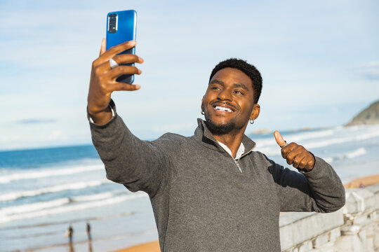 Man giving thumbs up while taking a selfie at the beach. Lifestyle concept.