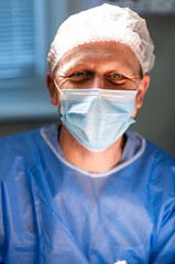 Smiling surgeon with protective mask. Close up of male doctor in operating room wearing mask