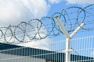Barbed wire fence on a background of blue sky with white clouds