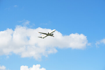 Airplane flying in the blue sky with white clouds in the air