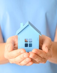 Hands holding a miniature blue house