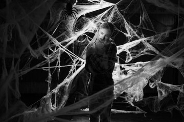 Creepy man with scary Halloween zombie makeup trapped spider webs, trying to scare. Dead guy in cob...