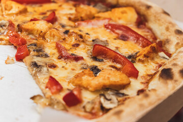 Delicious pizza topped with chicken, red peppers, mushrooms, and melted cheese displayed in a takeout box, perfect for food advertising or restaurant promotions.
