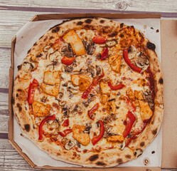 Delicious pizza topped with chicken, mushrooms, and red peppers in a takeout box. Ideal for food delivery services or casual dining scenes.