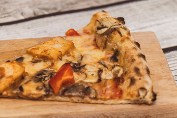 A delicious slice of pizza featuring cheese, mushrooms, and colorful vegetables, served on a wooden surface. Perfect for food photography and culinary presentations.