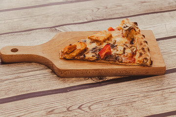 A slice of pizza topped with vegetables and cheese, resting on a wooden cutting board. Ideal for food blogs, menus, and culinary articles, showcasing delicious cuisine.