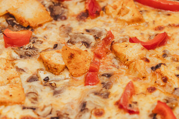 Delicious close-up view of pizza topped with chicken pieces, red bell pepper, and mushrooms. Ideal for food enthusiasts and culinary promotions.