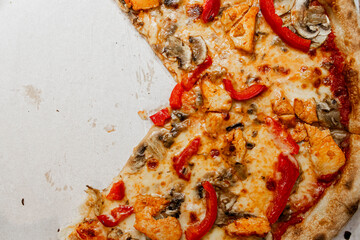 Delicious pizza slice topped with chicken, mushrooms, and red peppers showcasing melted cheese on a cardboard base, perfect for food photography or menu design.