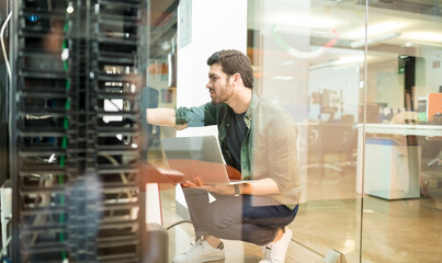 IT professional working with computer server rack and laptop in data center