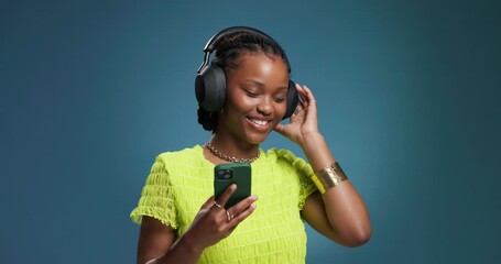 Black woman, headphones and dance with phone in studio for streaming, listening to music and audio. Person, energy and mockup space with mobile, moving rhythm and online playlist on blue background