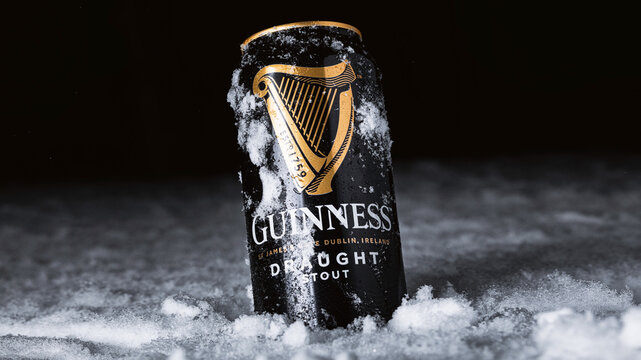 Dark Stout Can Resting in Fresh Snow During Winter Night. Guinness draught Irish beer
