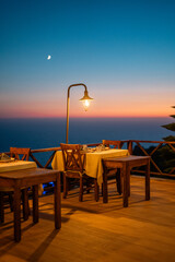 Empty restaurant table set for two, waiting for guests at sunset.


