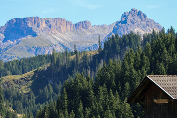 Wooden shelter nestle near the woods, watched by towering Dolomites