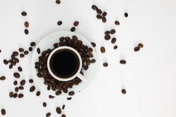 Cup of black coffee surrounded by roasted coffee beans on a white background. Top view of a fresh espresso concept.