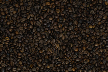 Close-up texture of roasted coffee beans. Dark brown background made of aromatic coffee seeds, top view.