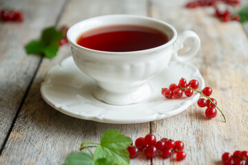 Red currant cake and a cup of aromatic tea in a porcelain cup on the table.