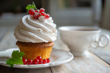 Red currant cake and a cup of aromatic tea in a porcelain cup on the table.