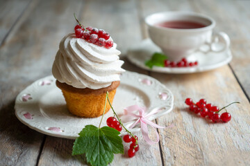 Red currant cake and a cup of aromatic tea in a porcelain cup on the table.