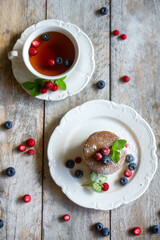Delicate pancakes with fruits and berries on a wooden table.
